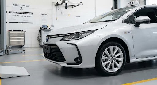 Close up photograph of front bumper and clean alloy wheel of modern silver Toyota hybrid taxi car in inspection depot bay